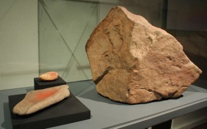 a) Bloque con pictografía estilo El Médano,cetáceo con balsero. Pescadores Tardíos. Colección Museo Augusto Capdeville, Taltal. b) Mortero y mano de moler con pigmento rojo.Piedra y óxido de fierro. Costa de Taltal. Pescadores Tempranos f Tardíos. Colección Museo Augusto Capdeville, Taltal.