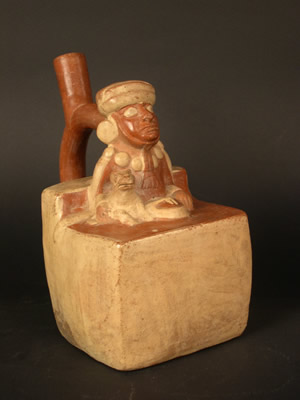 Botella asa-estribo: Gobernante-ancestro sentado acompañado de felino ataviado con túnica,capa, tocado y collar. Museo Larco, Lima – Perú / ML000641