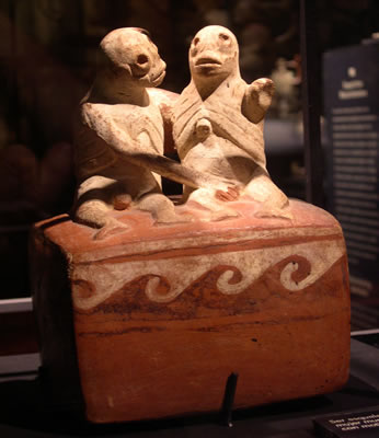 Botella asa-estribo : Ser esquelético masturbando a mujer muerta sin brazos, sobre plataforma con motivos de olas. Museo Larco, Lima – Perú / ML004316