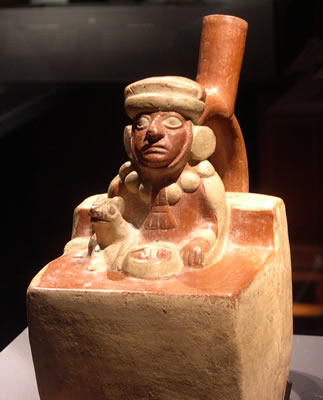 Botella asa-estribo: Gobernante-ancestro sentado acompañado de felino ataviado con túnica,capa, tocado y collar. Museo Larco, Lima – Perú / ML000641